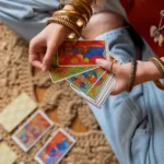 Coleção de baralhos de Tarot de Marselha abertos sobre uma mesa de madeira com cristais ao lado.