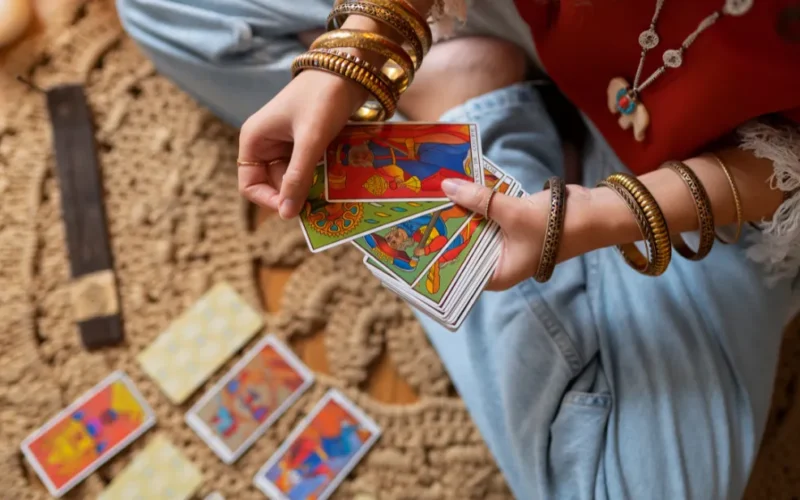 Coleção de baralhos de Tarot de Marselha abertos sobre uma mesa de madeira com cristais ao lado.