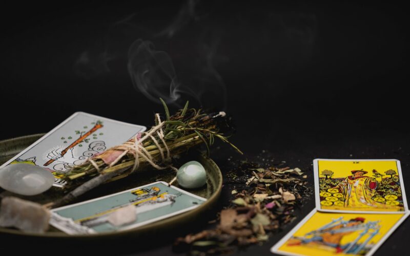 Variedade de incensos naturais e cristais dispostos ao lado de um baralho de tarot em um altar místico.