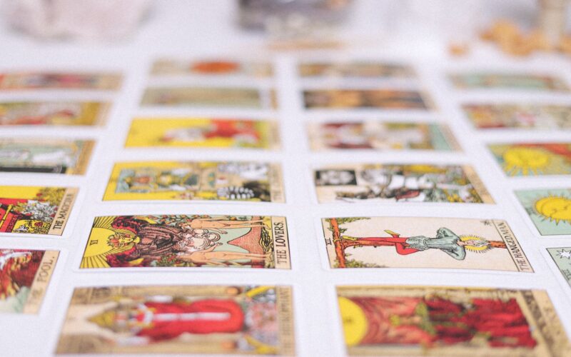 Mãos segurando três cartas de tarot sobre um fundo romântico com velas e cristais
