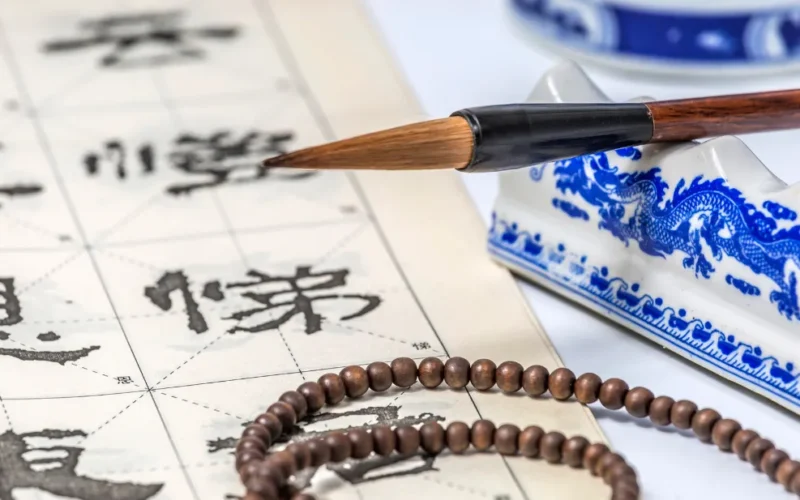 Tabela do Horóscopo Chinês com estátua dourada do Cavalo de Fogo rodeada por moedas chinesas da sorte e cristais.